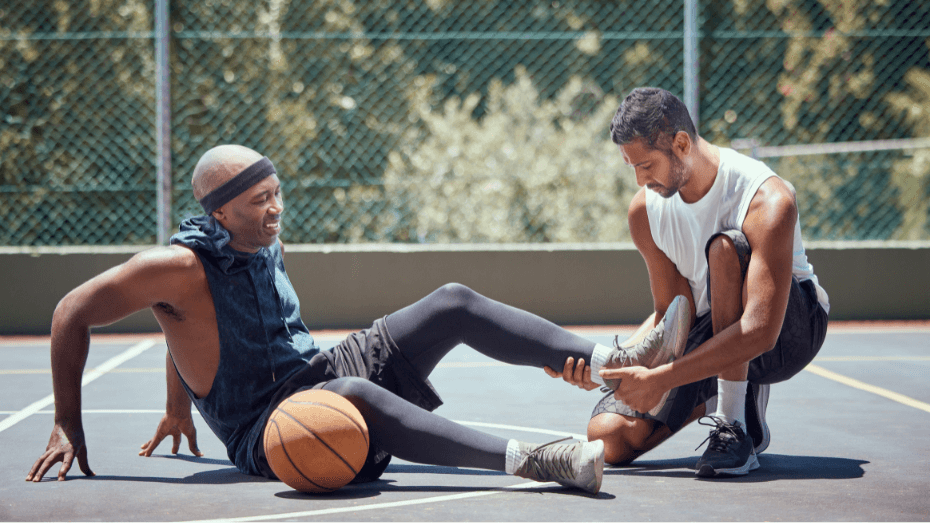 Basketball Verletzung am Sprunggelenk: Ein Mann kümmert sich um den verletzten anderen Mann