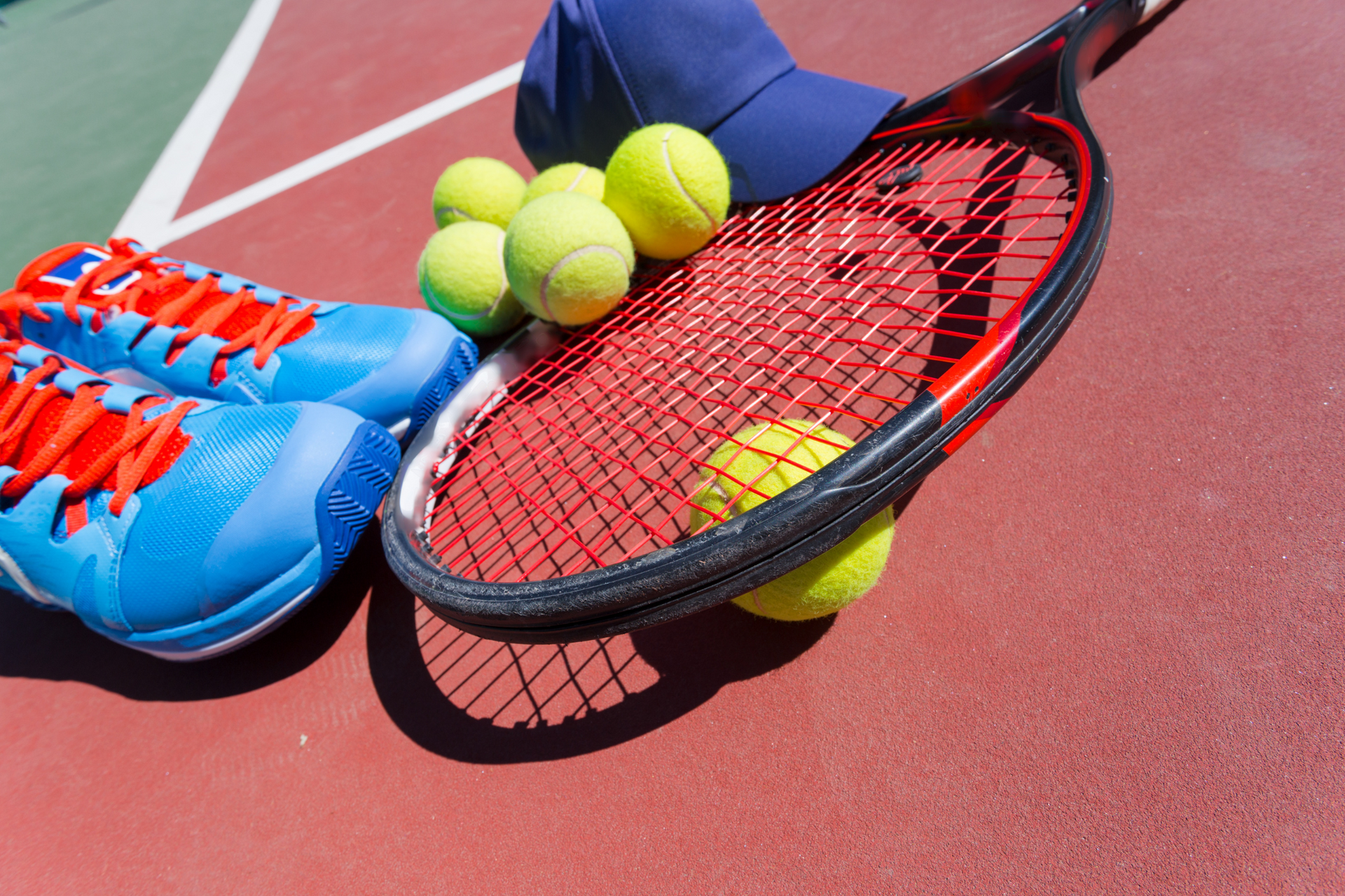 Tennisausrüstung aus Schuhen, Schläger, Tennisbällen und Kappe